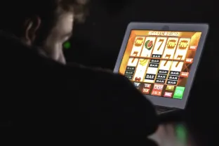 Gambling addicted man with glasses in front of online casino slot machine on laptop computer at night stock photo