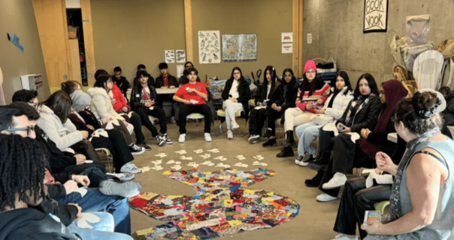 NYLD youth are sitting in a circle, surrounding artwork of a dove