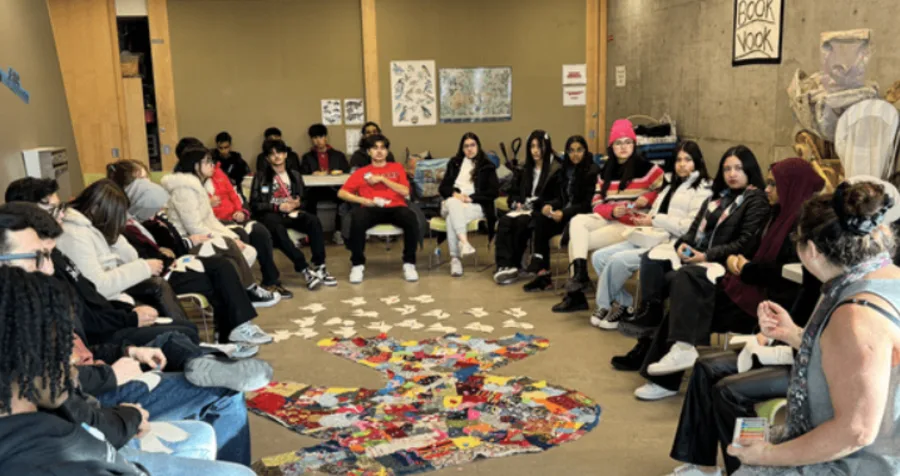 NYLD youth are sitting in a circle, surrounding artwork of a dove