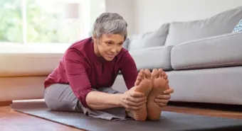 An older adult woman stretching on a yoga mat