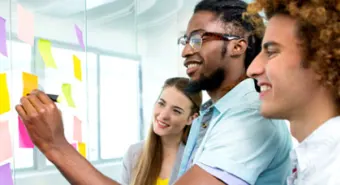 A group of three youth writing on post-it notes on the wall