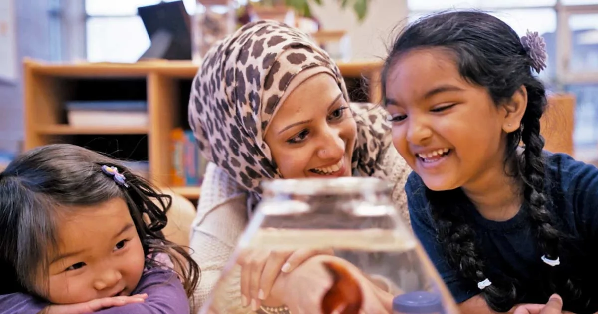 A childhood educator with her students with a fish bowl