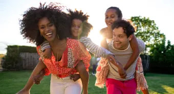 multicultural family of four plays in a park