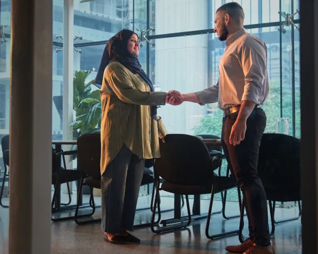 A newcomer engaged in a handshake with a YMCA Immigrant Services employee.