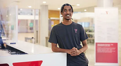 A smiling YMCA employee at a Y welcome desk.