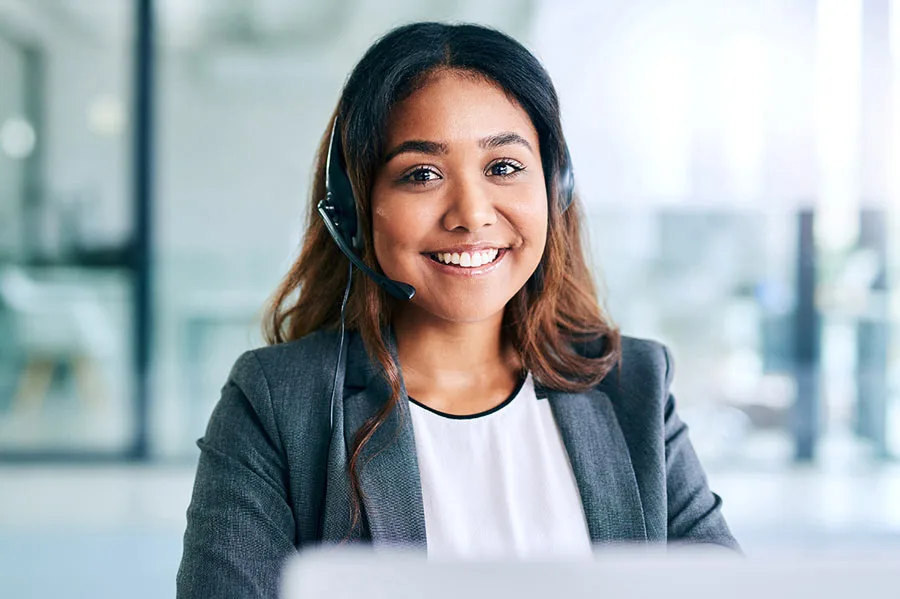 a woman wearing a headset at a computer, smiling