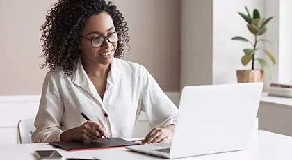 Woman taking notes and looking at laptop computer