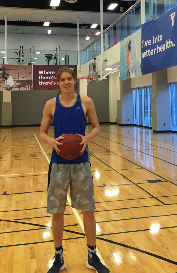 Mahiigan holding his basketball in Cooper Koo Family YMCA's basketball court