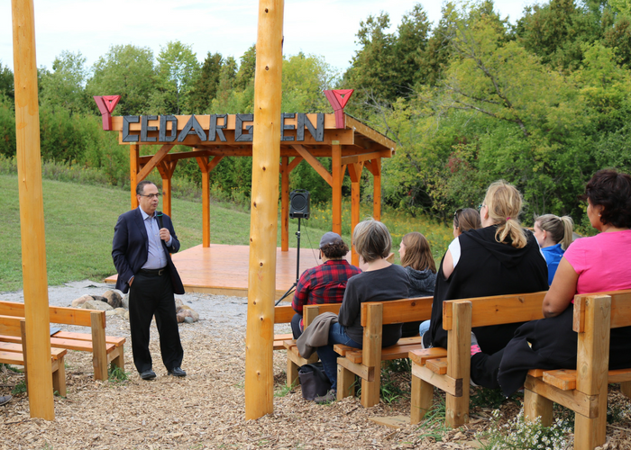 Medhat Mahdy stands in outdoor auditorium speaking to staff sitting on benches