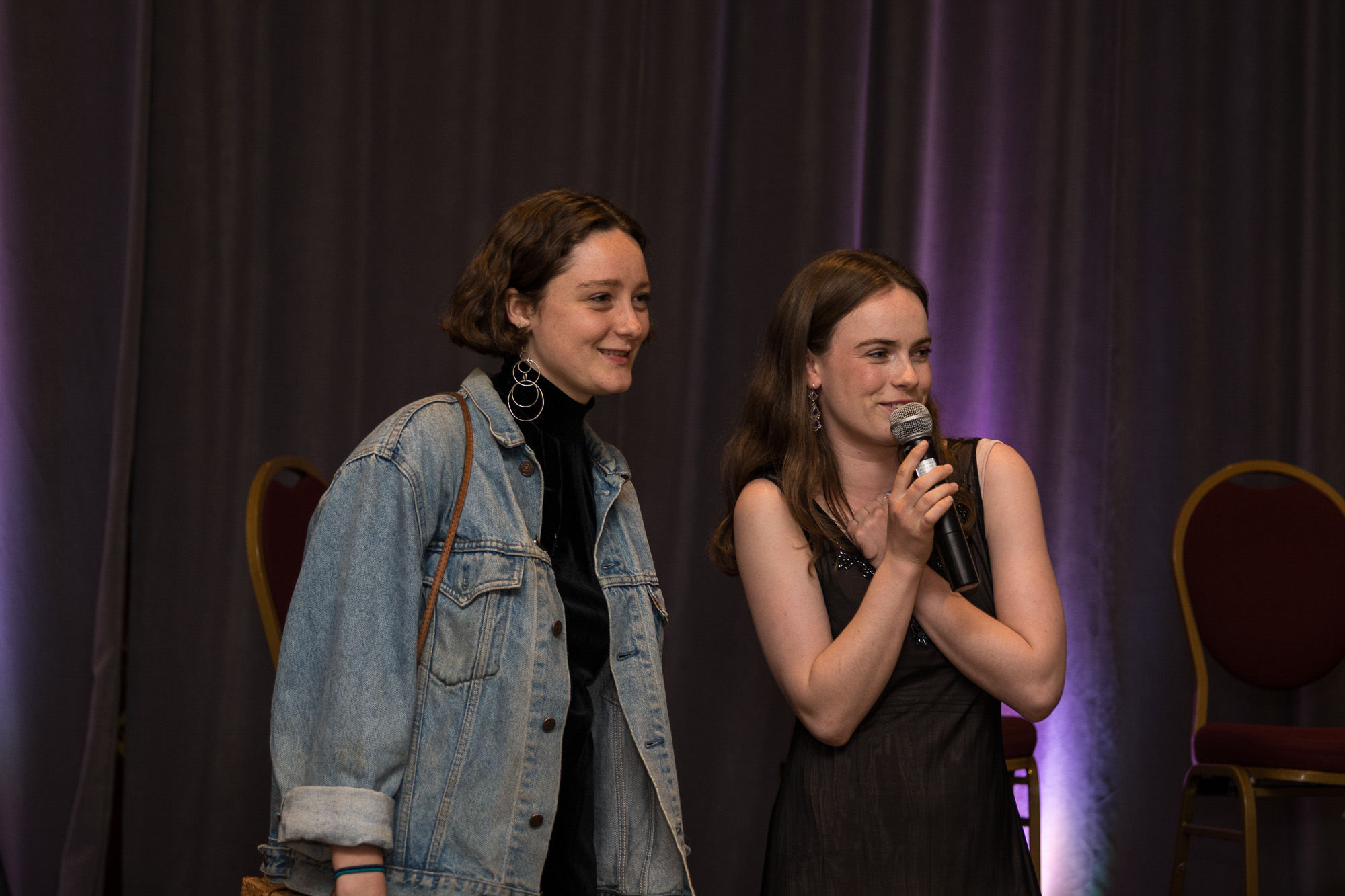 Charlotte holding a microphone on stage with Hailey