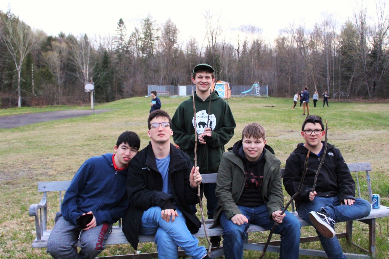 Group of 5 teen boys holding up sticks