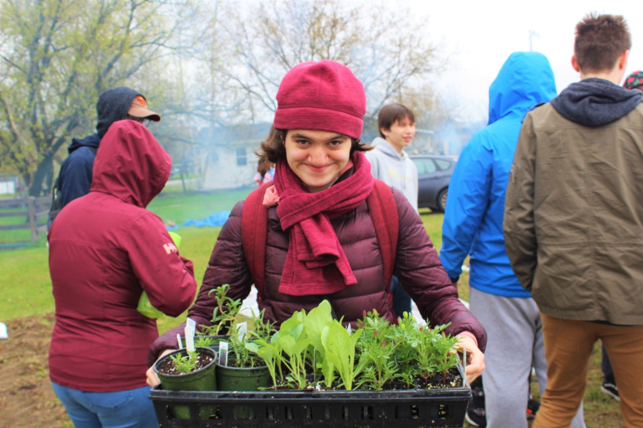 Teenage girl holding up a tray full of plants