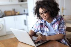 An individual wearing glasses is seated in front of a laptop