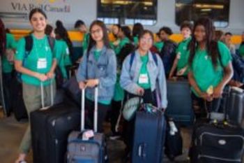 Group of youth in front of a train with suitcases